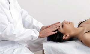 chiropractor placing hands on the patient's forehead