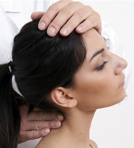 Chiropractor examining the back of the neck of a patient placing one hand on the top of the head