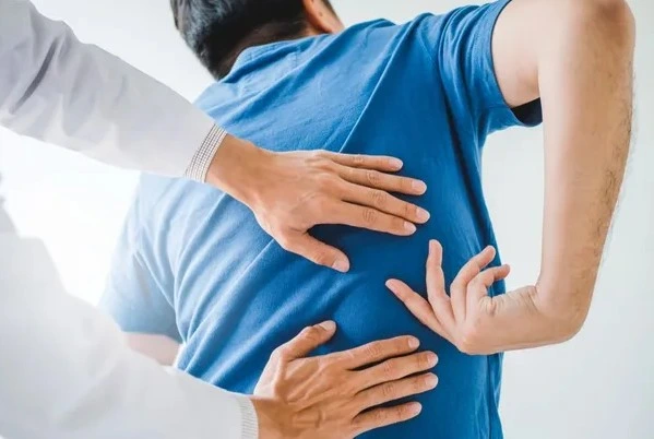 chiropractor checking the back of patient in blue shirt
