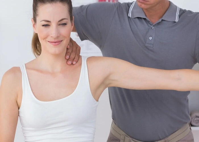 Chiropractor performing shoulder mobility test.