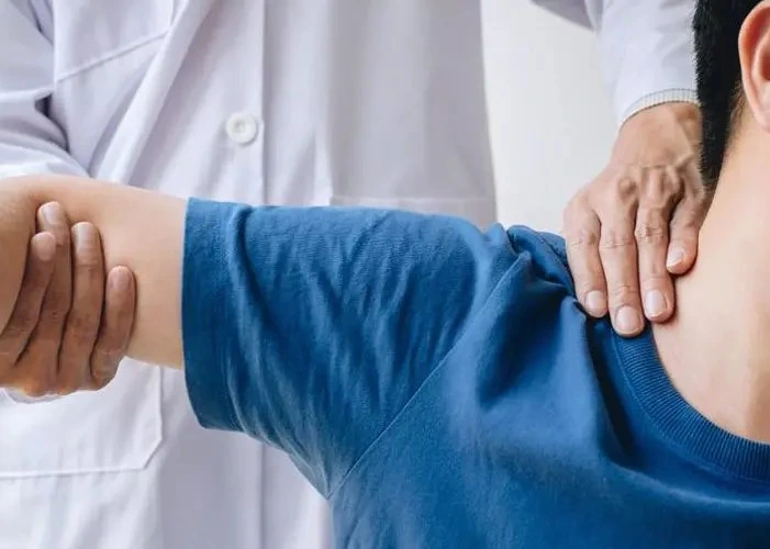 Chiropractor assessing shoulder and neck mobility.