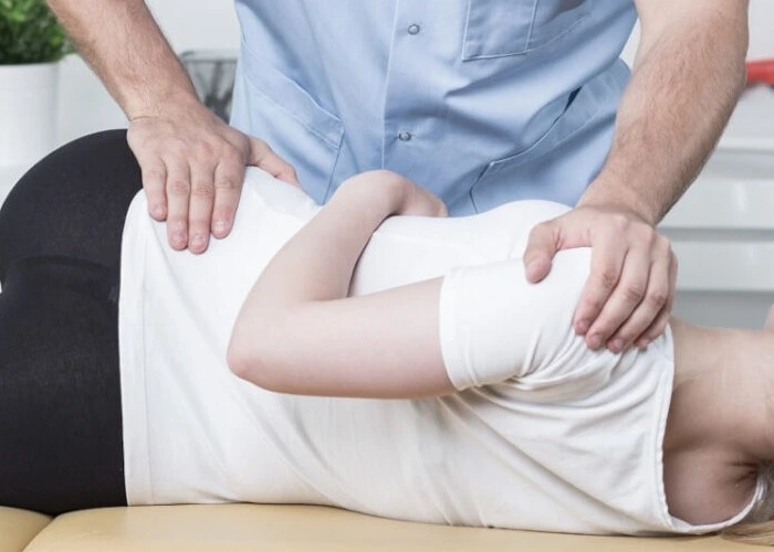 Chiropractor adjusting patient’s spine.