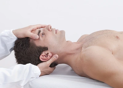 Chiropractor assessing a patient lying on his back