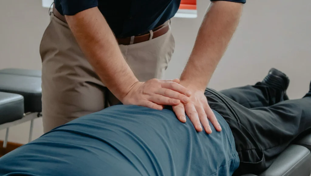 Chiropractor applying pressure to lower back.